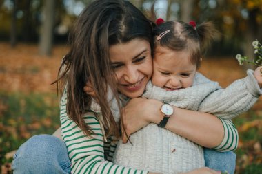 Anne ve kızı güz parkında birlikte vakit geçiriyorlar, mutlu kucaklaşmalar. Sonbahar doğası. Anneler Günü kavramı. Metin alanını kopyala