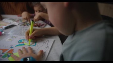 Bir erkek ve bir kız bir masada birlikte oturuyorlar, çizim yapmak için keçeli kalem kullanıyorlar. Onlar eğlenceli aktivitelerine odaklanıyorlar ve sanat yaratmaktan zevk alıyorlar.