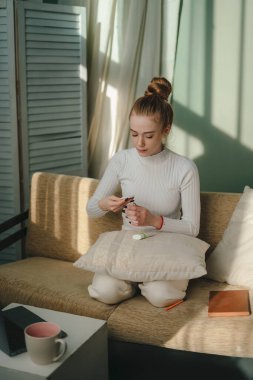 İçeride rahat bir koltukta oturan, banyo yaptıktan sonra vücut losyonu kullanan sağlıklı bir kadın. Sağlıklı cilt. Hijyen ve güzellik kavramı