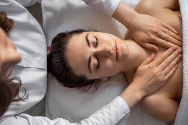 Bir kadın spa 'da rahatlatıcı bir masaj seansının tadını çıkarıyor. Muhtemelen şımartılıyor, rahatlıyor ve tazeleniyor.