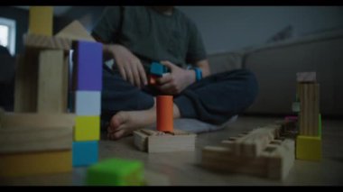 Bir çocuk evin içinde tahta bloklarla oynar, yaratıcılığı teşvik eder ve neşeli bir eğitim ortamında öğrenmeyi teşvik eder.