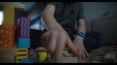 Bir çocuk neşe içinde oynar, renkli blokları olan yaratıcı yapılar inşa eder ve eğlenceli bir yere davet eder.