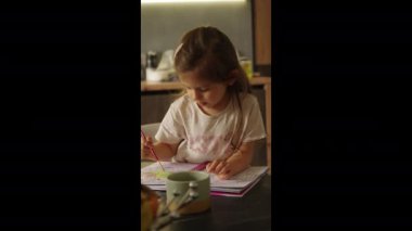 Genç bir kız, dikkat çekici yaratıcılığını ve hayal gücünü sergileyen renkli renkli kitabına derinden odaklanır.