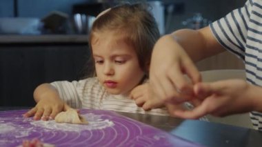 Genç bir çocuk, bir yetişkinin yanında yemek pişirme, yaratıcılık, neşe ve eğlenceyi birlikte teşvik eder.