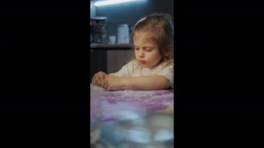 Genç bir çocuk masadaki sanatsal bir projeye derinden konsantre olup hem yaratıcılık hem de odak seviyesini gösteriyor.