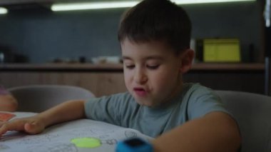 Masadaki bir resmi boyamaya derinden odaklanmış genç bir çocuk yaratıcılık ve konsantrasyon gösteriyor..