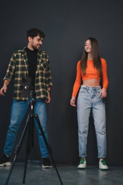 İki genç insan, bir stüdyo ortamında eğlenceli bir fotoğraf çekiminde birlikte poz veriyor ve eğleniyorlar.