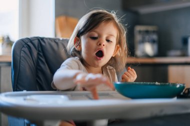 Neşeli ve neşeli bir çocuk, neşeli ve çağdaş bir mutfak ortamında farklı yemek türlerini keşfediyor.