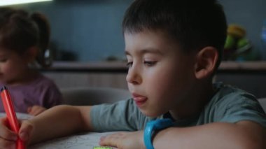 İki çocuk yaratıcı bir şekilde sakin bir ev ortamında sanatsal ifadelerini sergiliyorlar..
