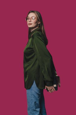 Moda modası geçmiş bir model, kendine güvenen bir zeytin yeşili gömlek ve sıradan bir kot pantolon sergiliyor.