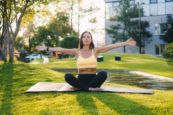 Bir kadın barışçıl bir şekilde doğanın ortasında meditasyon yapıyor. Derin iç huzuru ve farkındalığı somutlaştırıyor.