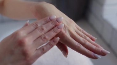 Huzurlu bir ortamda nemlendirici krem süren zarif ve narin ellerin yakın plan görüntüsü.