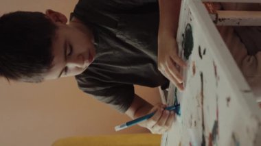 Genç bir çocuk resim yapmaya derinden odaklanmış, yaratıcılığını ve eşsiz sanatsal ifadesini güzel bir şekilde sergiliyor.