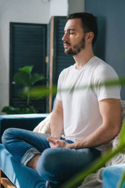 Bir adam sessiz sedasız, yemyeşil yemyeşil bir alanda düşünceli meditasyon yapıyor.