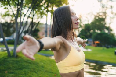 Huzurlu bir anda, bir kadın kollarını sonuna kadar açar, hem doğayla hem de kendisiyle güzelce bağ kurar.