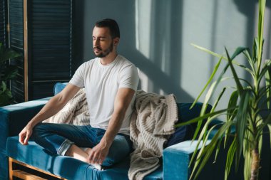 Huzurlu ve huzurlu bir meditasyon anı şık bir oturma odasındaki rahat bir kanepede sergilenir.