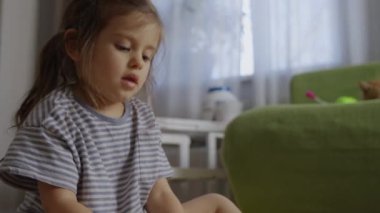 Genç bir kız, rahat bir oturma odasında renkli oyuncaklarıyla meşgul olarak oyun zamanından zevk alır.