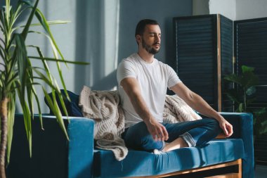 Huzurlu bir oturma odasında meditasyon yapan bir adam zihinsel refahı ve rahatlığı teşvik eder.