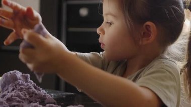 Neşeli, genç bir çocuk canlı mor modelleme kiliyle yaratıcı bir oyun oynuyor ve hayal güçlerini sergiliyor.