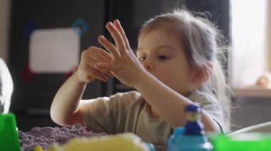 Genç bir çocuk çeşitli renkli oyuncaklarla neşeyle oynar ve yaratıcılığını keşfeder, hayal gücünü gösterir ve odaklanır.