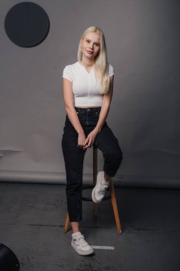 Genç bir kadın modern bir stüdyoda dururken şık ve modaya uygun bir şekilde poz veriyor.