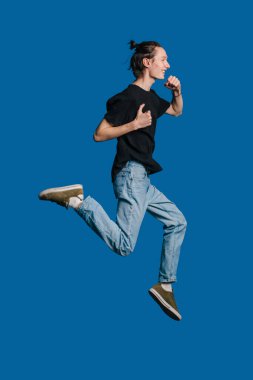 Genç bir adam elinde aperatifle neşeyle koşuyor, enerjisini gösteriyor ve bu eğlenceli aktivitenin tadını çıkarıyor.