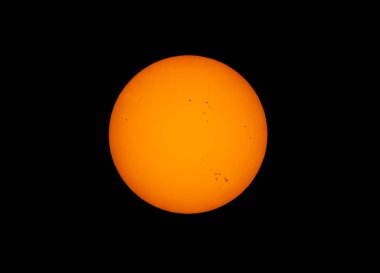 Turuncu renkli öğleden sonra güneşi, siyah bir zemin üzerinde ev yapımı güneş filtresi kullanarak birçok güneş lekesi ile parlıyordu..