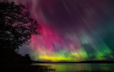 Kuzey Işıkları (Aurora Borealis) güzel soğuk bir sonbahar gecesinde Ottawa nehri boyunca gökyüzünü aydınlatır.