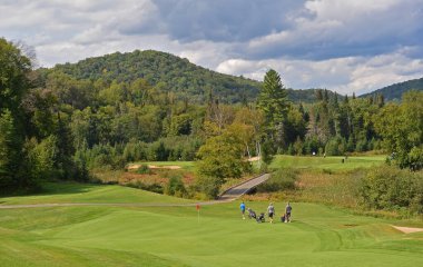 Kanada 'da güzel bir yaz gününde bulutlu gökyüzü ile yuvarlanan tepelerin arasında yeşil bir golf sahası