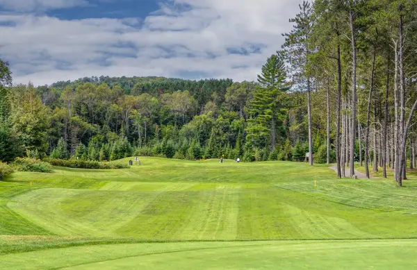 Kanada 'da güzel bir yaz gününde bulutlu gökyüzü ile yuvarlanan tepelerin arasında yeşil bir golf sahası