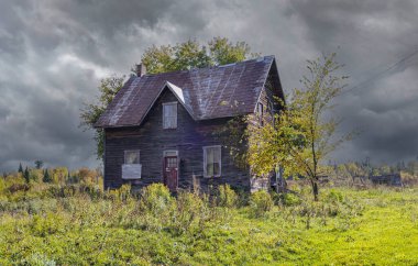 Quebec, Kanada kırsalındaki bir çiftlik bahçesinde ilkbaharda terk edilmiş eski bir çiftlik evi.