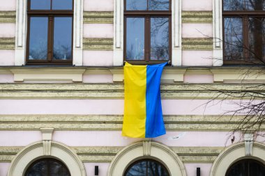 RIGA, LATVIA. 5 Aralık. Seçici odak fotoğrafı. Pencereye asılı Ukrayna bayrağı.