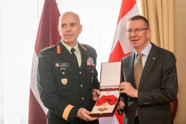 RIGA, LATVIA. 13 Mayıs 2024. Letonya Cumhurbaşkanı Edgars Rinkevic (R), Kanada Genelkurmay Başkanı Wayne Eyre 'ye (L) Letonya' nın en yüksek onurunu sundu..