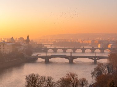 Prag 'ın üzerinde kışın soğuk şafağı. Vltava nehrinin üzerinde altın parıltı ve kış sisi var. Köprü ve tarihi bir kasaba var. Prag, Çek Cumhuriyeti