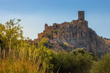 Kum taşından yapılmış terk edilmiş, eski bir dağ kasabası olan Craco 'nun pitoresk bir manzarası. Craco, 20. yüzyılın sonlarında meydana gelen deprem yüzünden terk edilmiş bir hayalet kasaba. Matera ili, Basilicata, İtalya