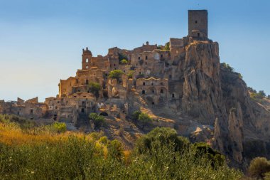 Kum taşından yapılmış terk edilmiş, eski bir dağ kasabası olan Craco 'nun pitoresk bir manzarası. Craco, 20. yüzyılın sonlarında meydana gelen deprem yüzünden terk edilmiş bir hayalet kasaba. Matera ili, Basilicata, İtalya