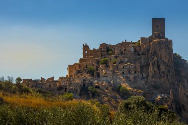 Kum taşından yapılmış terk edilmiş, eski bir dağ kasabası olan Craco 'nun pitoresk bir manzarası. Craco, 20. yüzyılın sonlarında meydana gelen deprem yüzünden terk edilmiş bir hayalet kasaba. Matera ili, Basilicata, İtalya