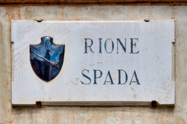  İtalya 'nın Foligno kentindeki Rione Spada' nın mermer plaketinde, bölgenin mirasını simgeleyen çıplak bir kılıç amblemi yer alıyor..