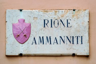 İtalya, Umbria, Foligno 'daki Rione Ammanniti' nin mermer plaketinde pembe arka planda iki çapraz kılıç bulunuyor.. 