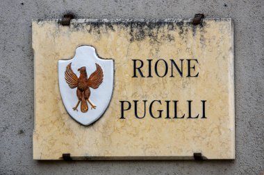  İtalya 'nın Umbria kentindeki Foligno kentindeki Rione Pugilli' nin mermer plaketinde bölgenin mirasını simgeleyen bir kartal amblemi yer alıyor. Ghibelline şehri Todi ile ilişkili olan kartal bölgenin tarihsel bağlantılarını yansıtıyor.
