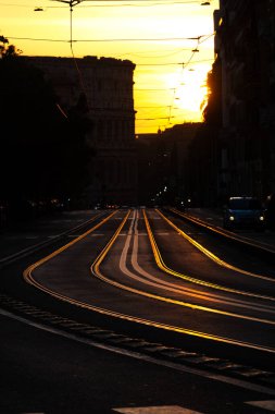Gün batımı ışığı Via Labicana 'daki tramvay raylarından yansıyor. Kolezyum silueti Roma, İtalya' da arka planda..