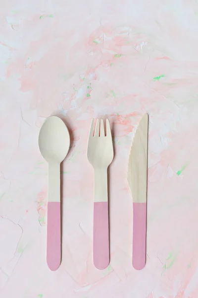 Disposable eco friendly bamboo cutlery on pink background, spoon, knife and fork cutlery. Zero waste concept, recycling. Plastic free alternative for environmental protection. Copy space