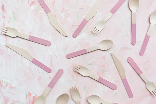Disposable eco friendly bamboo cutlery pattern on pink background, spoon, knife and fork cutlery. Zero waste concept, recycling. Plastic free alternative for environmental protection