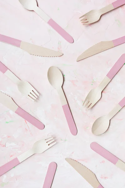 Disposable eco friendly bamboo cutlery pattern on pink background, spoon, knife and fork cutlery. Zero waste concept, recycling. Plastic free alternative for environmental protection