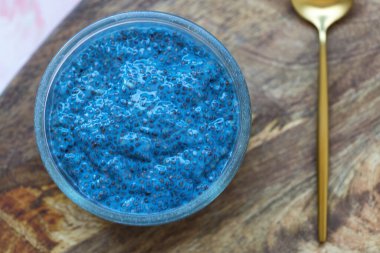 Mavi spirulina chia tohumu puding kasesi ve kaşık. Süper yiyecek ve vejetaryen gıda konsepti. Kapat, üst görünüm