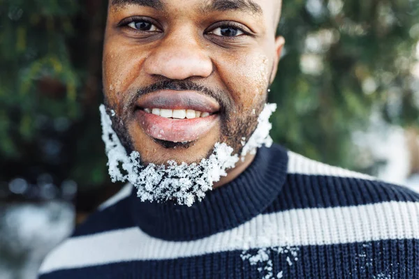 开朗有趣的非洲男人 留着雪白的胡子 喜欢冬天的天气 穿着条纹毛衣 街上的肖像画 公园里有雪 生活方式 城市生活理念 复制空间 免版税图库照片