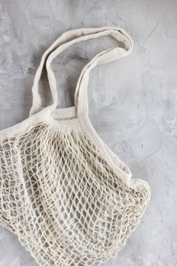 Reusable shopping mesh bag on gray background. Zero waste, no plastic, eco friendly shopping, recycling concept. Flat lay, close up