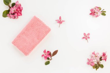 New folded microfiber cloth for cleaning on white with spring flowers background. Cleaning micro fabric for dusting and polishing. Domestic household cleaning service concept. Top view