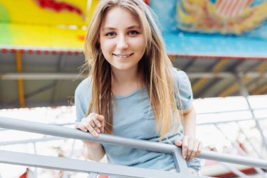 Happy young Gen Z woman in an amusement park, smiling. Copy space. Summer time