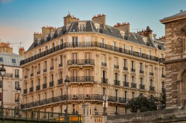Paris 'te cam pencereleri ve balkonları olan yaşlanmış gri bir konut binasının dışı..